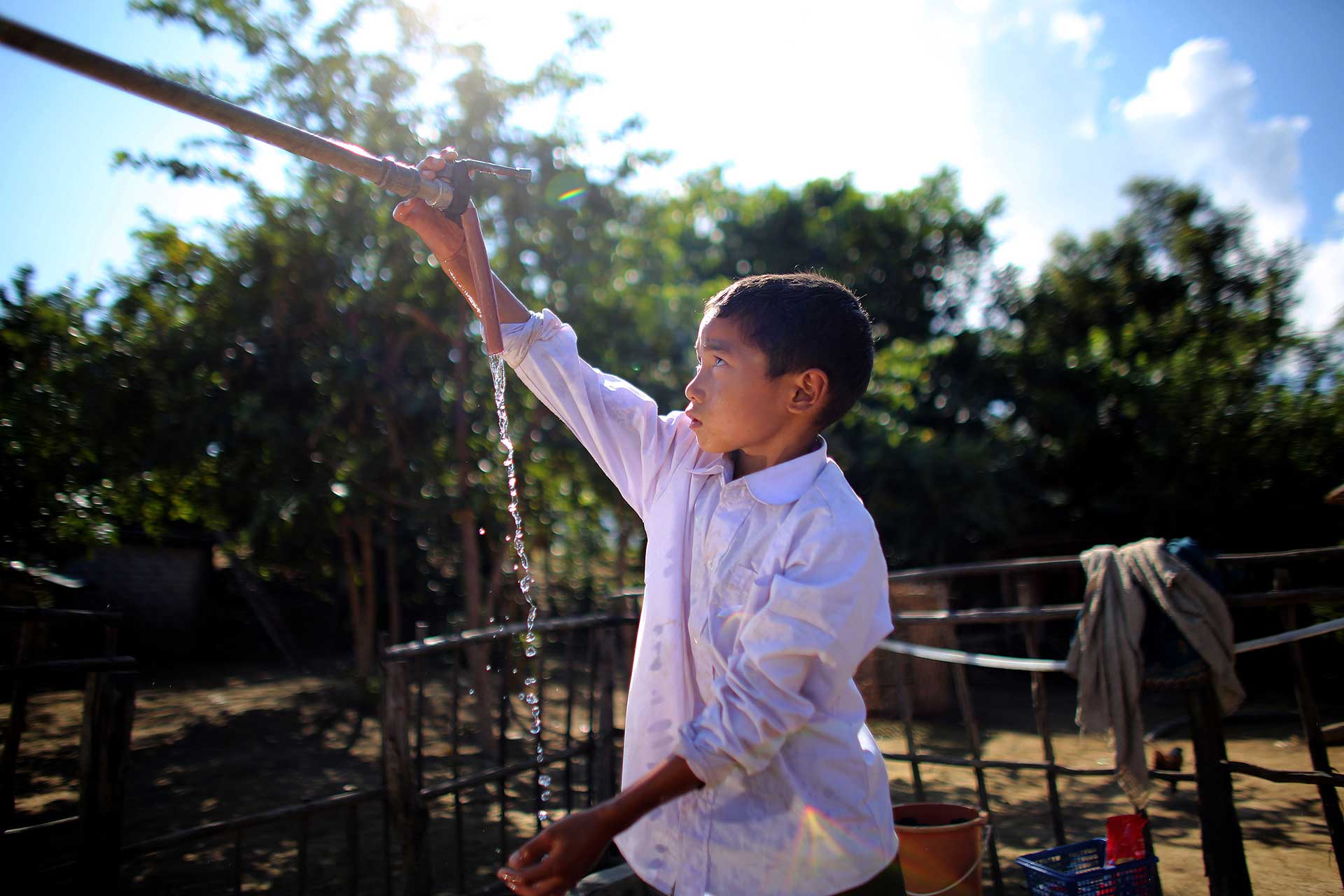 Lao village boy at a water pump